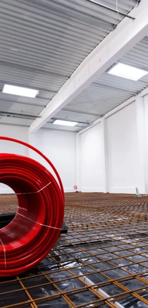 Coiled red pipe in modern unfinished warehouse interior.